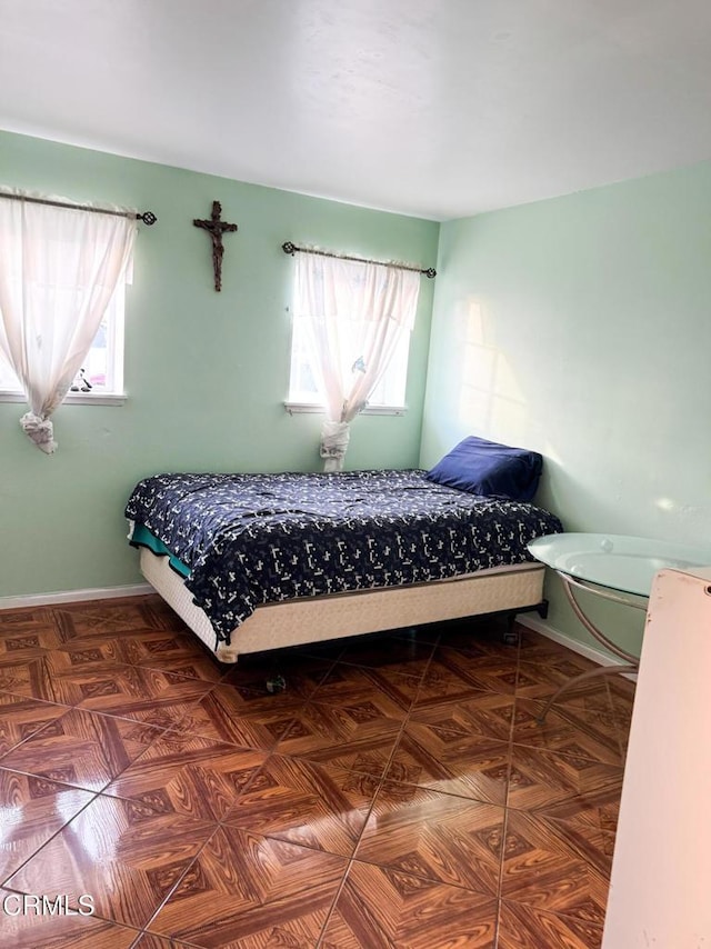 bedroom featuring multiple windows and dark parquet flooring