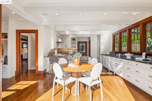 dining room featuring beamed ceiling, ornamental molding, and light wood-type flooring