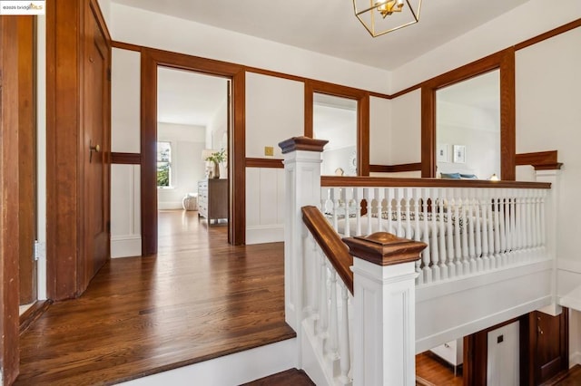 stairs with hardwood / wood-style floors and a notable chandelier