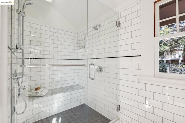 bathroom featuring lofted ceiling and a shower with shower door