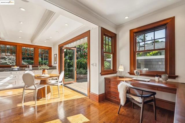 doorway with beamed ceiling, ornamental molding, and light hardwood / wood-style floors