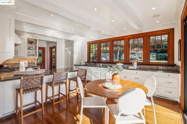 dining room with sink, beam ceiling, ornamental molding, and hardwood / wood-style flooring