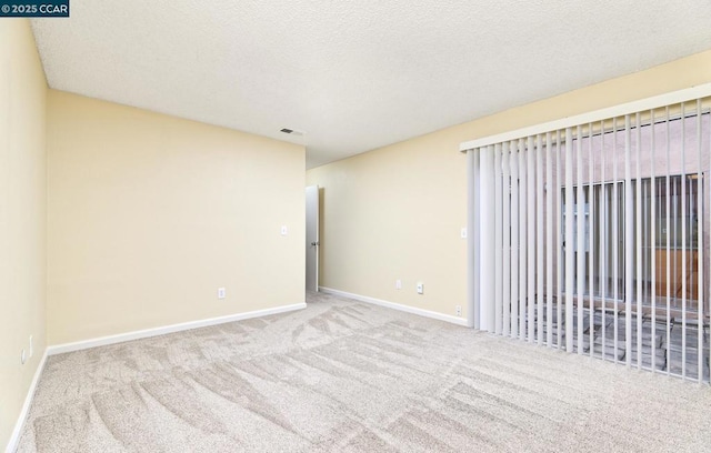 unfurnished room featuring light colored carpet and a textured ceiling