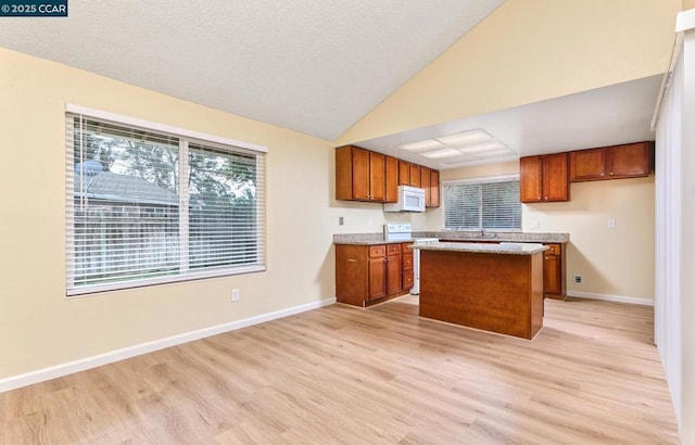 kitchen with sink, a center island, vaulted ceiling, white appliances, and light hardwood / wood-style floors