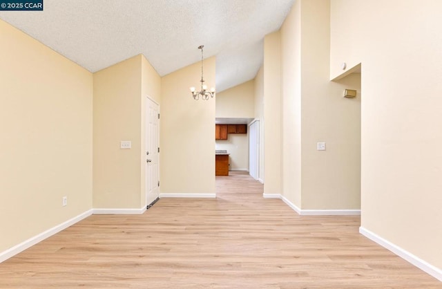 interior space featuring an inviting chandelier, lofted ceiling, a textured ceiling, and light wood-type flooring