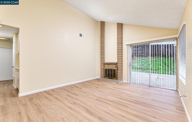 unfurnished living room featuring high vaulted ceiling, a textured ceiling, a fireplace, and light hardwood / wood-style floors