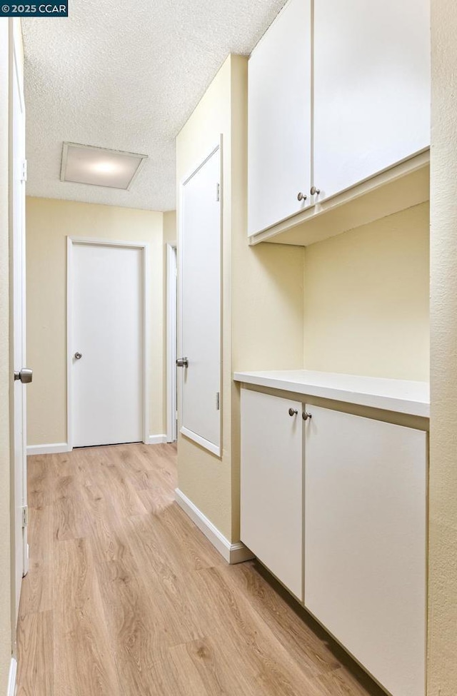 corridor featuring light hardwood / wood-style flooring and a textured ceiling