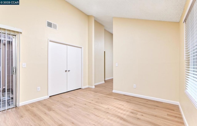 unfurnished bedroom featuring vaulted ceiling, light hardwood / wood-style floors, and a closet