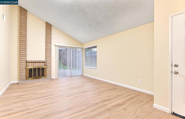 unfurnished living room with a fireplace, vaulted ceiling, a textured ceiling, and light wood-type flooring