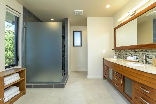 bathroom with a shower with door, vanity, tile patterned flooring, and backsplash