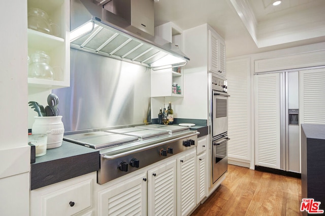 kitchen with island range hood, light hardwood / wood-style floors, white cabinets, and appliances with stainless steel finishes