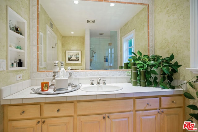 bathroom with tiled shower and vanity