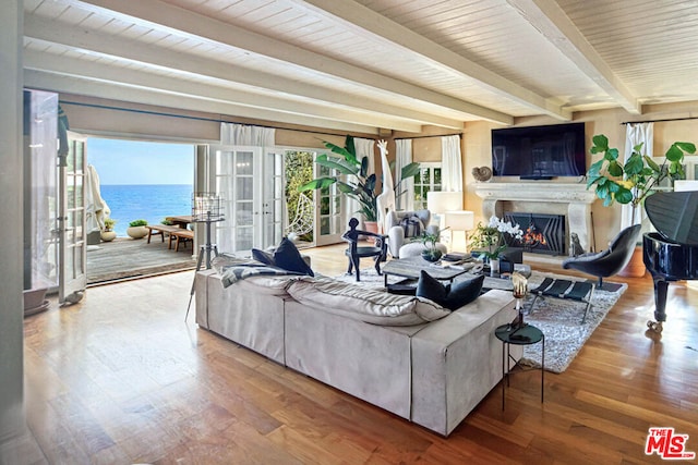 living room with hardwood / wood-style floors, beam ceiling, a water view, wooden ceiling, and french doors