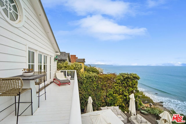 balcony with an outdoor hangout area, a beach view, and a water view