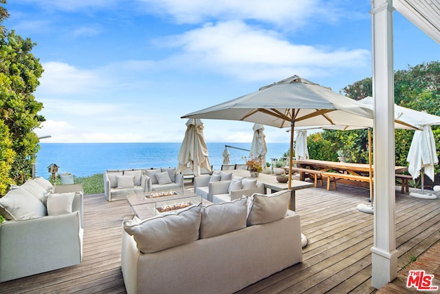 wooden deck featuring a water view and an outdoor living space with a fire pit