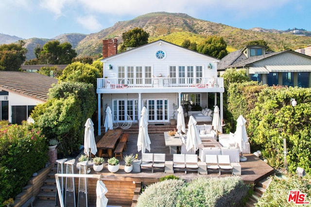 rear view of house with outdoor lounge area, french doors, a balcony, and a deck with mountain view