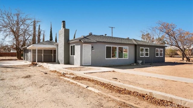 ranch-style home with board and batten siding, a chimney, and an attached garage