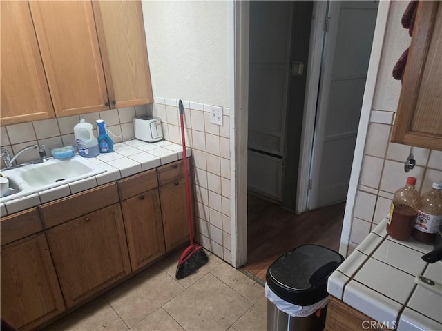 interior space featuring tile walls, sink, light tile patterned floors, and tile countertops