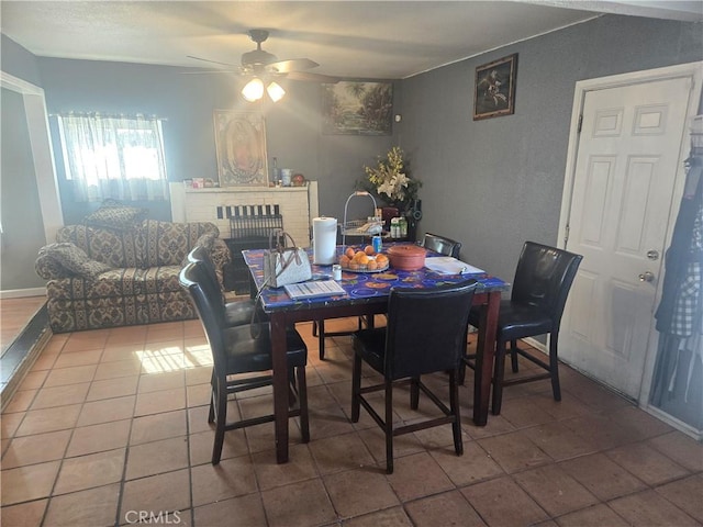 tiled dining space with a fireplace and ceiling fan