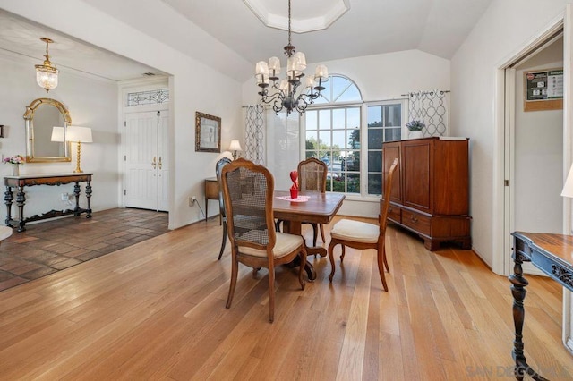 dining space featuring light hardwood / wood-style flooring, a chandelier, and vaulted ceiling