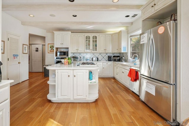 kitchen featuring stainless steel appliances, tasteful backsplash, a center island, and beam ceiling