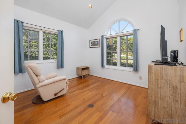 sitting room with hardwood / wood-style flooring and high vaulted ceiling