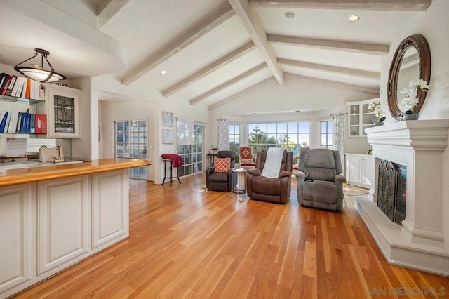 living room featuring lofted ceiling with beams, a premium fireplace, and light hardwood / wood-style floors