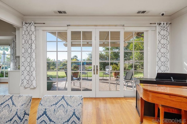 doorway with french doors, crown molding, and light hardwood / wood-style flooring