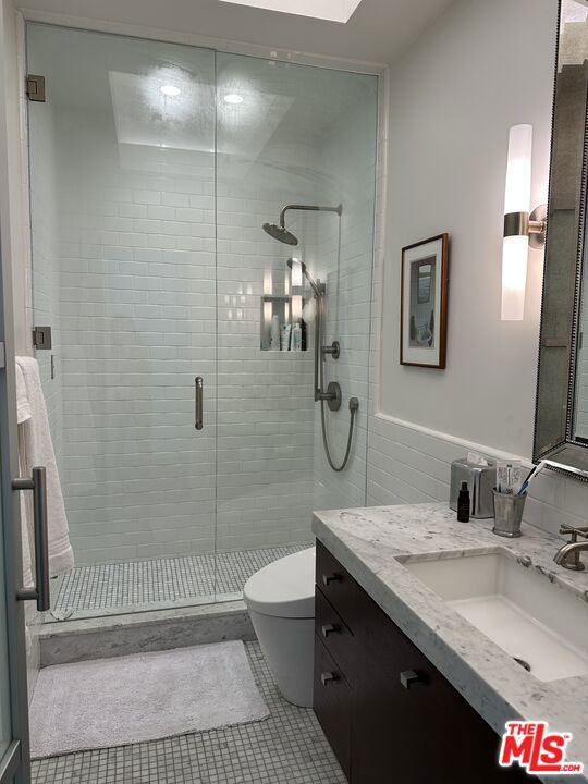 bathroom with tile walls, vanity, an enclosed shower, tile patterned floors, and toilet