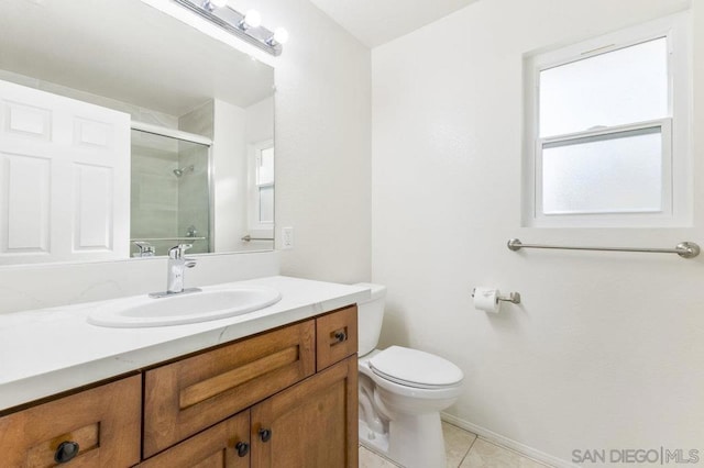 bathroom featuring vanity, a healthy amount of sunlight, tile patterned floors, and toilet