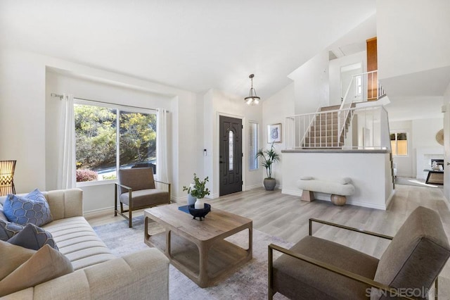 living room with high vaulted ceiling and light hardwood / wood-style flooring