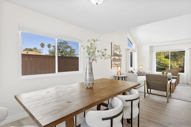 dining room with lofted ceiling and light wood-type flooring