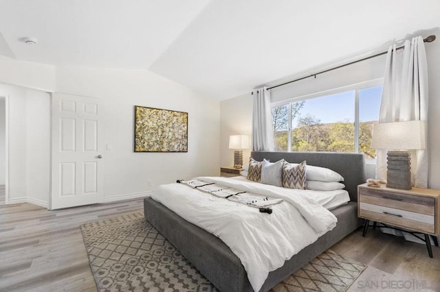 bedroom with lofted ceiling and light hardwood / wood-style floors