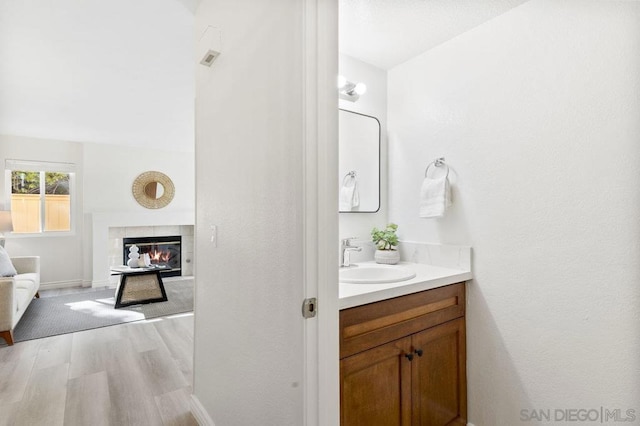 bathroom featuring a tiled fireplace, vanity, and wood-type flooring