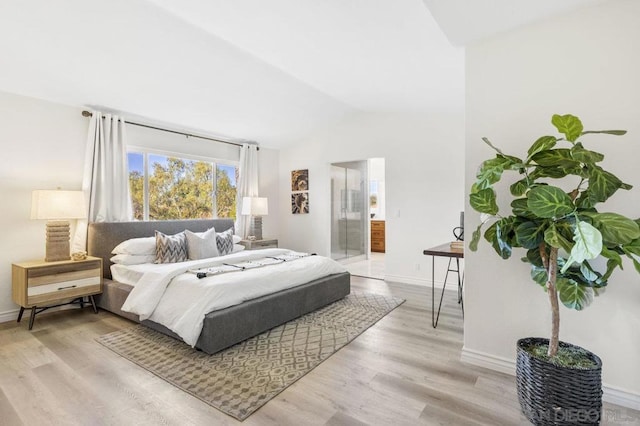 bedroom featuring lofted ceiling, connected bathroom, and light hardwood / wood-style floors