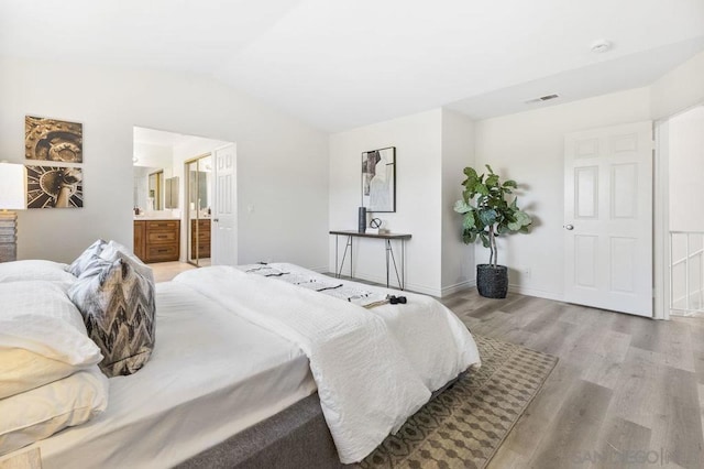 bedroom with lofted ceiling, ensuite bath, and light hardwood / wood-style floors