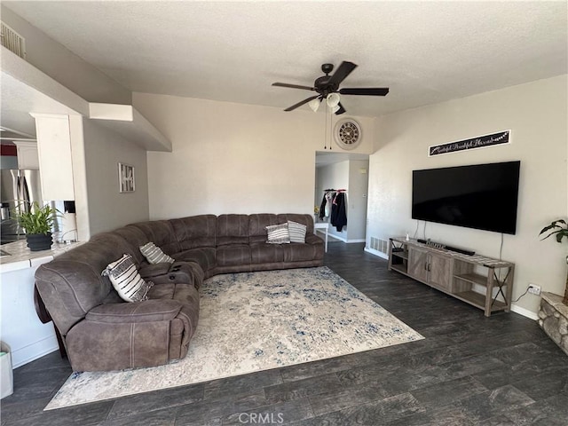 living room featuring dark wood-type flooring, ceiling fan, and a textured ceiling