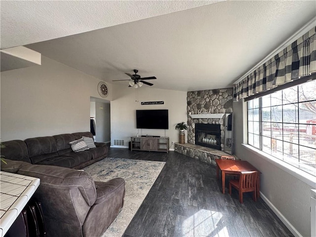 living room featuring lofted ceiling, a textured ceiling, a stone fireplace, and dark hardwood / wood-style flooring