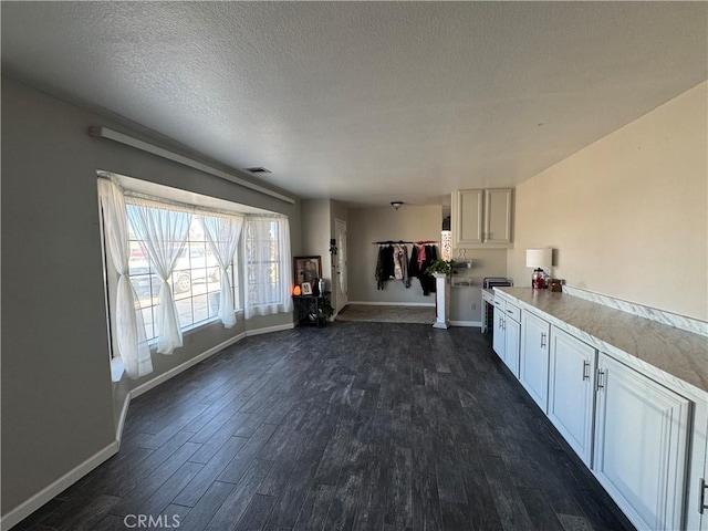 interior space featuring white cabinetry, dark hardwood / wood-style floors, and a textured ceiling