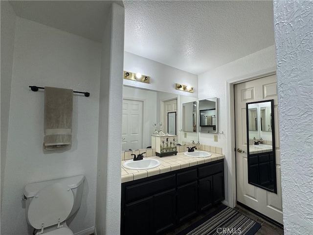 bathroom with vanity, toilet, and a textured ceiling