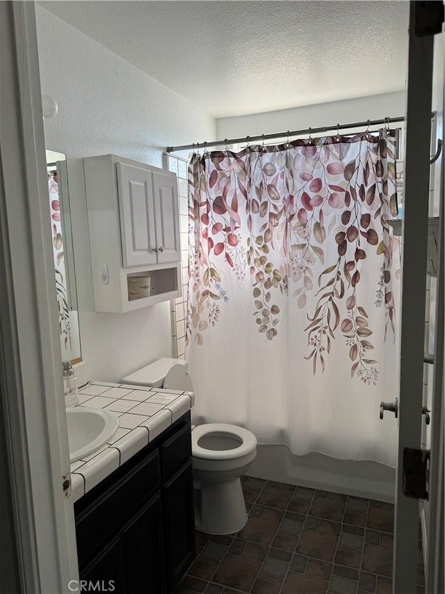 full bathroom with vanity, toilet, shower / tub combo, and a textured ceiling