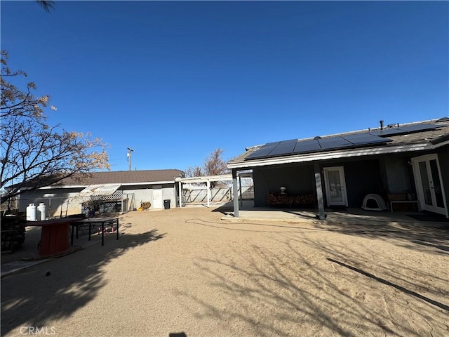 rear view of house with a patio area and solar panels