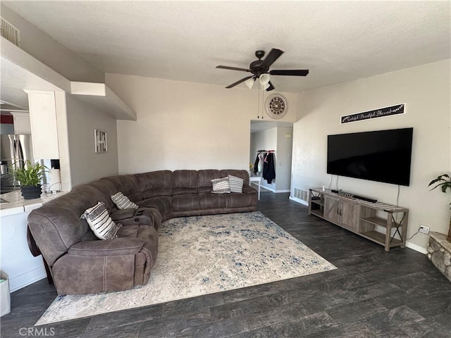 living room featuring dark wood-type flooring, ceiling fan, and a textured ceiling