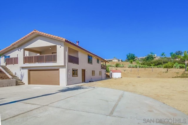 view of side of home with a garage and a balcony