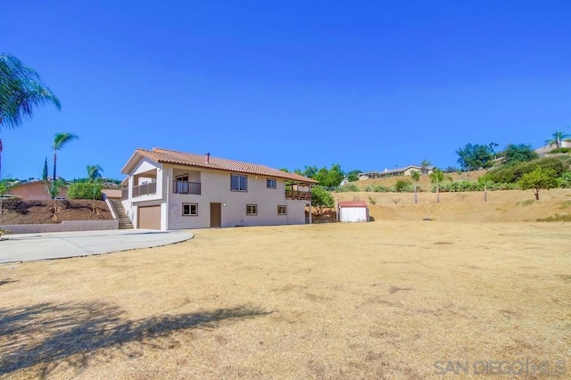 back of property featuring a garage and a balcony