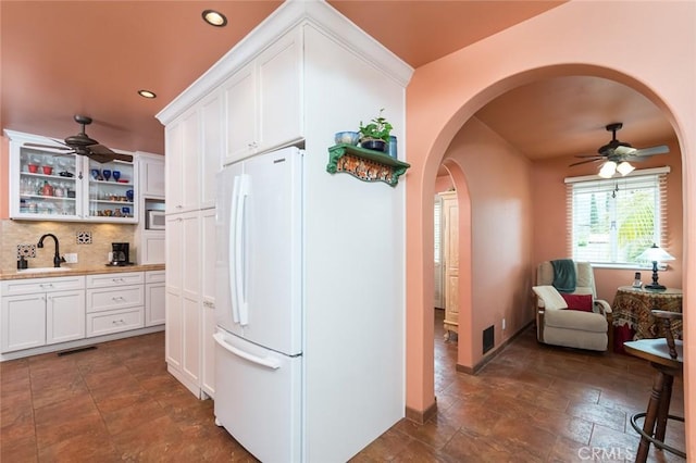 kitchen with white cabinetry, sink, backsplash, white fridge, and ceiling fan