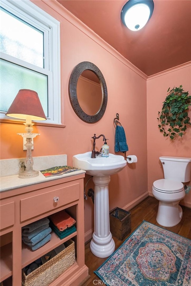 bathroom with crown molding, wood-type flooring, and toilet