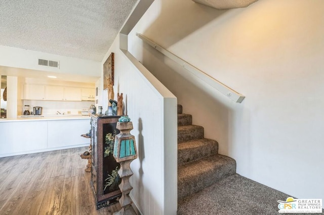 staircase featuring wood-type flooring and a textured ceiling