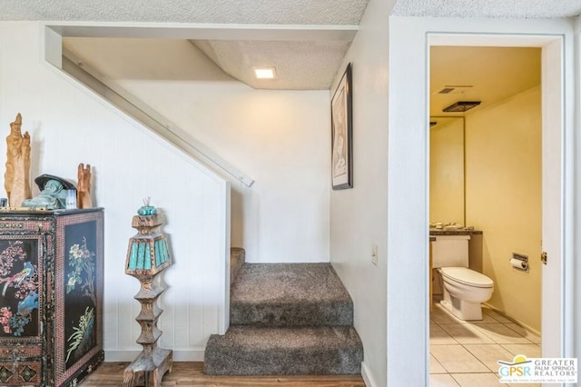 staircase featuring tile patterned floors and a textured ceiling