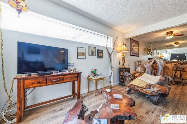 living room with ceiling fan, light hardwood / wood-style flooring, and a textured ceiling